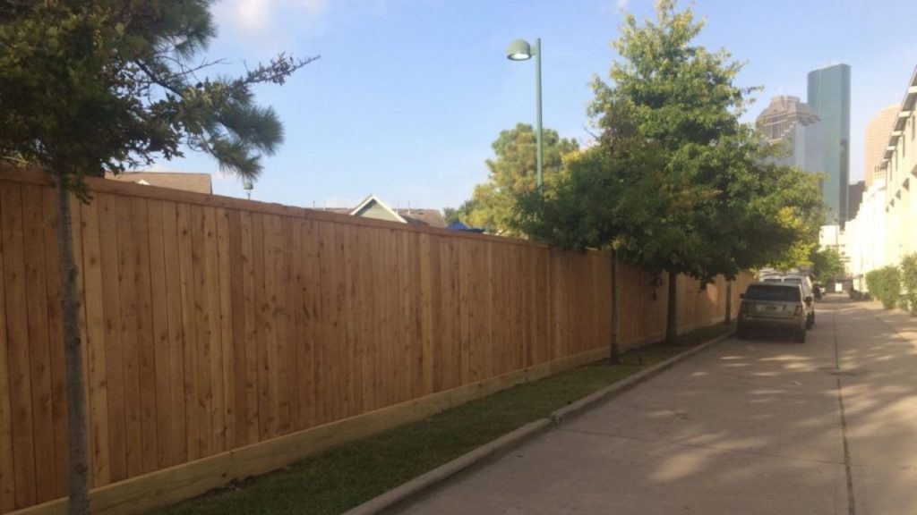Newly installed wood perimeter fence around a condominium community with the Houston skyline in the background.